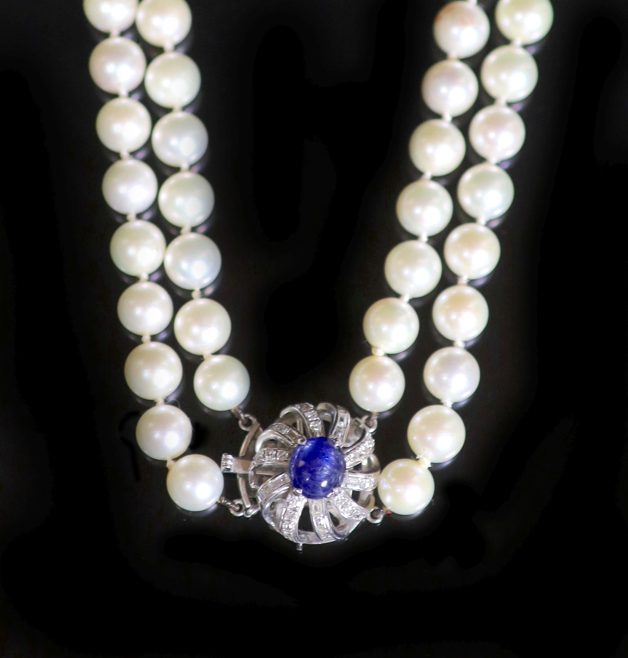 A two-row uniform cultured pearl necklace with 14K white gold, sapphire and diamond set flower clasp,
